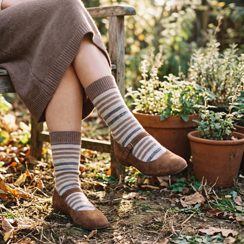 Calcetines altos de rayas de lana y cashmere en beige y gris con merceditas de ante, en una silla de jardín